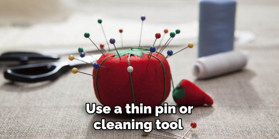 Use a thin pin or cleaning tool 